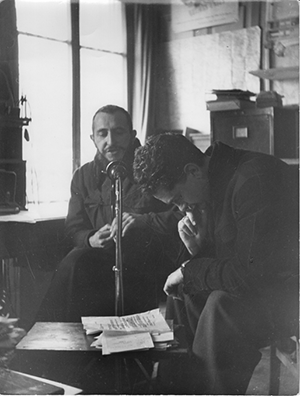 Black and white image two men in front of a microphone during an AP Radio broadcast for Luxembourg and Neuilly-Plaisance, France.
